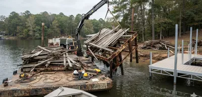 Old dock being removed from lake shoreline with work barge